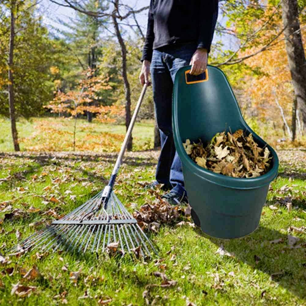 Eine Person harkt Laub im Garten an einem sonnigen Herbsttag. Laub wird in einem Eimer gesammelt, umgeben von buntem Herbstlaub.