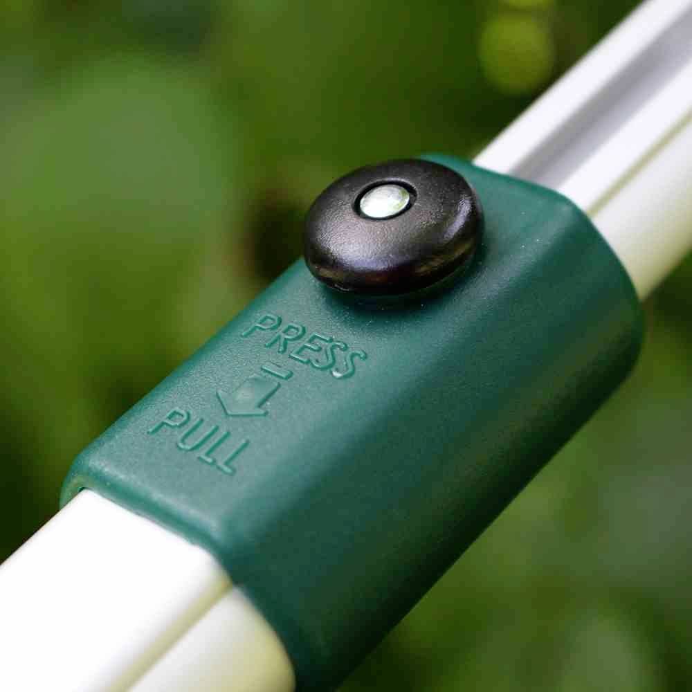 Ein grüner Knopf auf einem Metallstab mit den Anweisungen 'Press' und 'Pull', vermutlich Teil eines Mechanismus oder Werkzeugs.