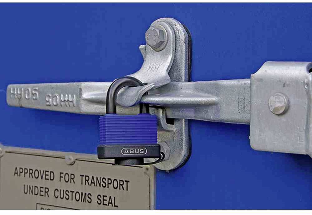Ein blaues Vorhängeschloss sichert die Tür eines Containers. An der Tür hängt ein Schild mit der Aufschrift 'Approved for transport under customs seal'.