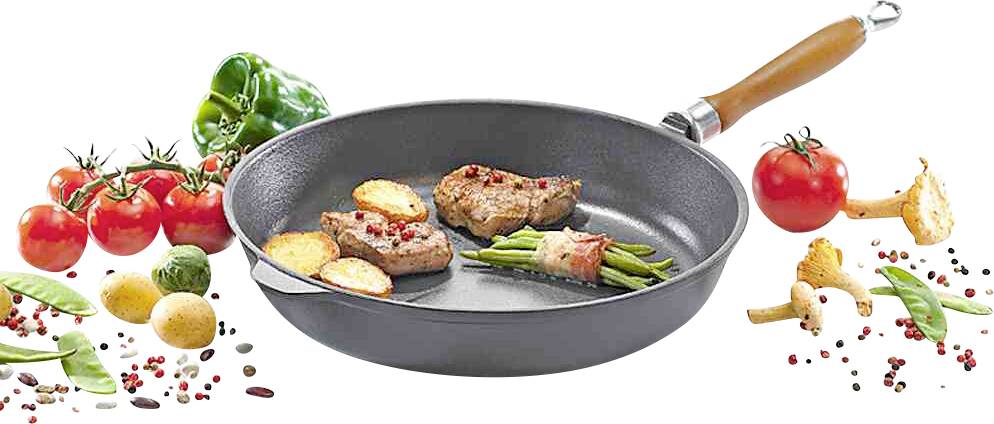 Pfanne mit gebratenen Fleischstücken, Kartoffelscheiben und grünen Bohnen, umgeben von frischem Gemüse wie Tomaten, Paprika und Pilzen.