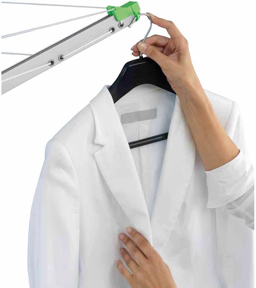 Eine Person hängt ein weißes Sakko an einem Kleiderbügel auf einen Wäschetrockner.