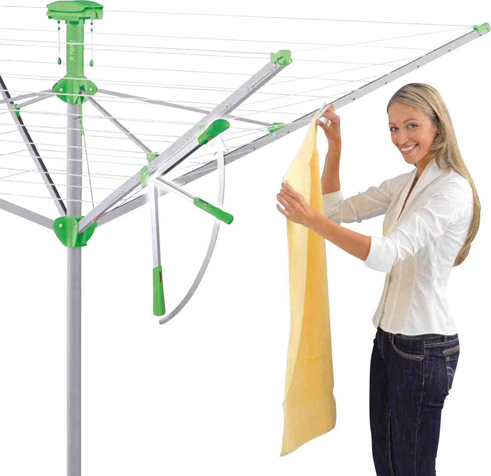 Frau hängt ein Handtuch auf einem Wäscheschirm im Freien auf. Der Wäscheschirm ist geöffnet und hat mehrere ausgebreitete Leinen.