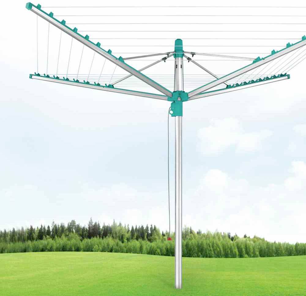Ein grüner Wäscheschirm steht auf einer grünen Wiese mit bewaldetem Horizont und bewölktem Himmel im Hintergrund.