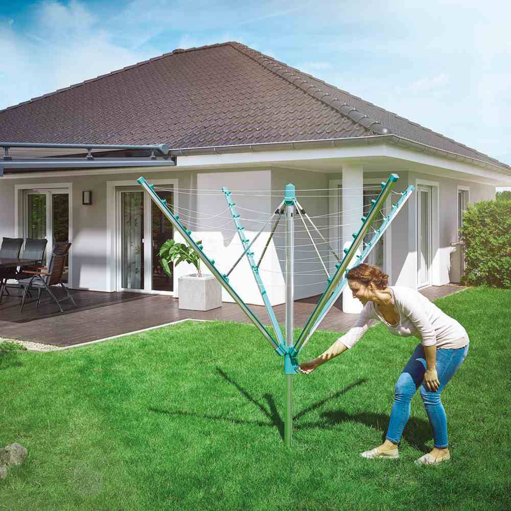 Frau im Garten stellt einen Wäscheschirm ein vor einem modernen Einfamilienhaus mit Terrasse.