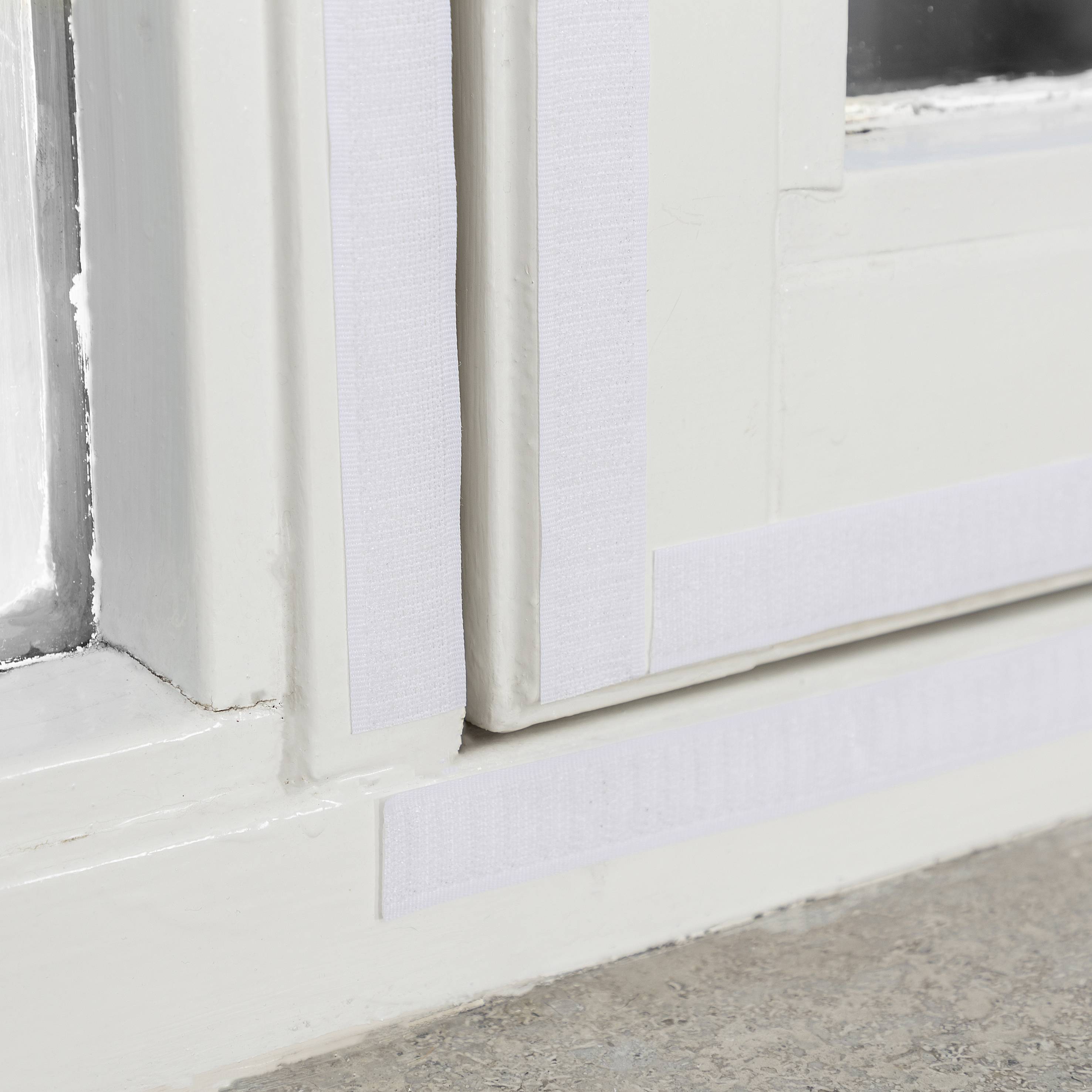 Ein Fensterrahmen ist mit weißem Dichtungsband versehen, das zwischen Rahmen und Wand angebracht ist, um Zugluft zu verhindern.