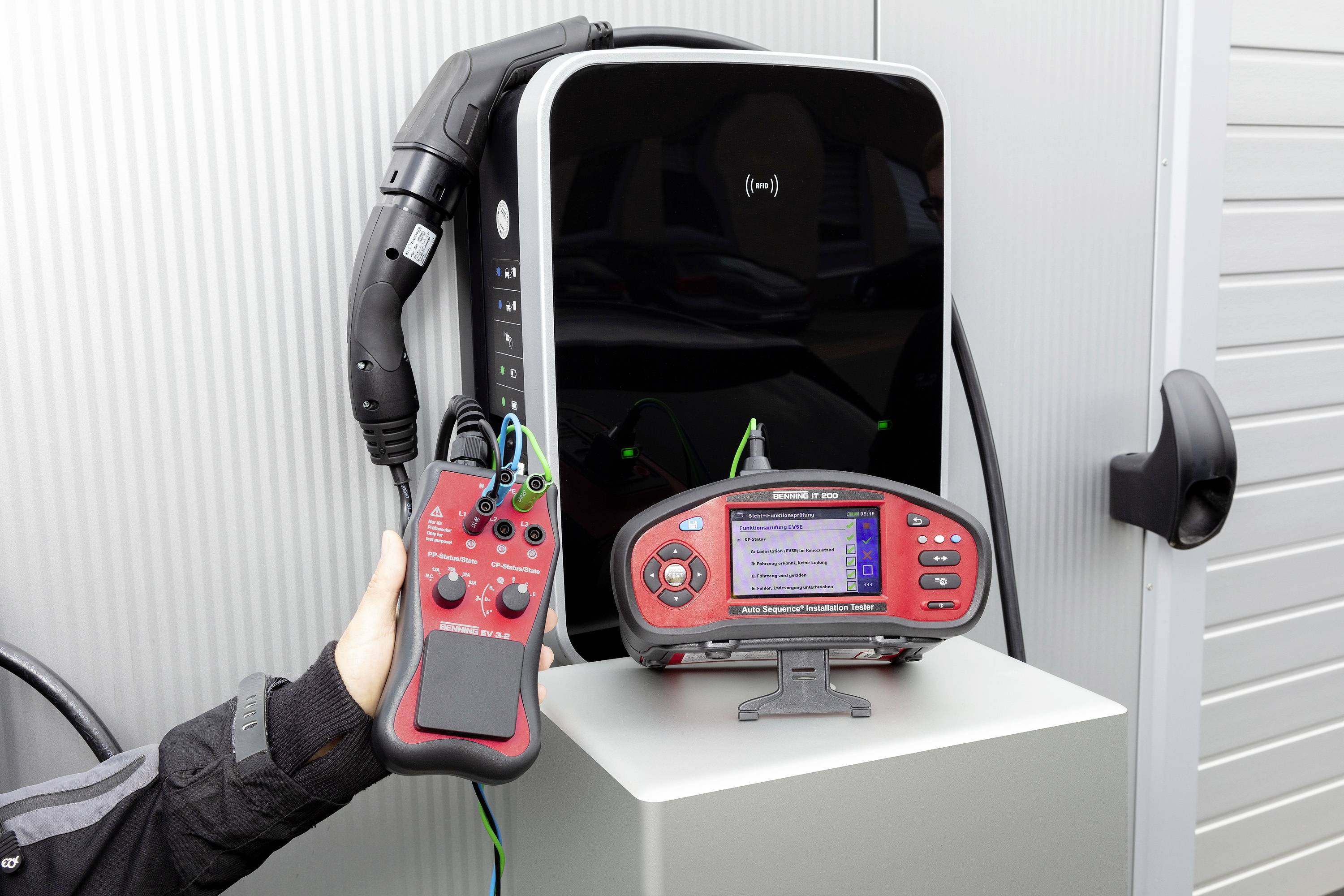 Ein Ladegerät für Elektrofahrzeuge wird mit einem Prüfgerät getestet. Eine Hand hält das Prüfgerät, das Ergebnisse anzeigt.