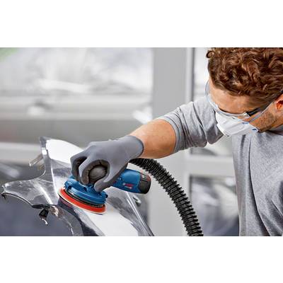 Eine Person schleift eine Metalloberfläche mit einem elektrischen Schleifgerät. Sie trägt Schutzbrille, Maske und Handschuhe.