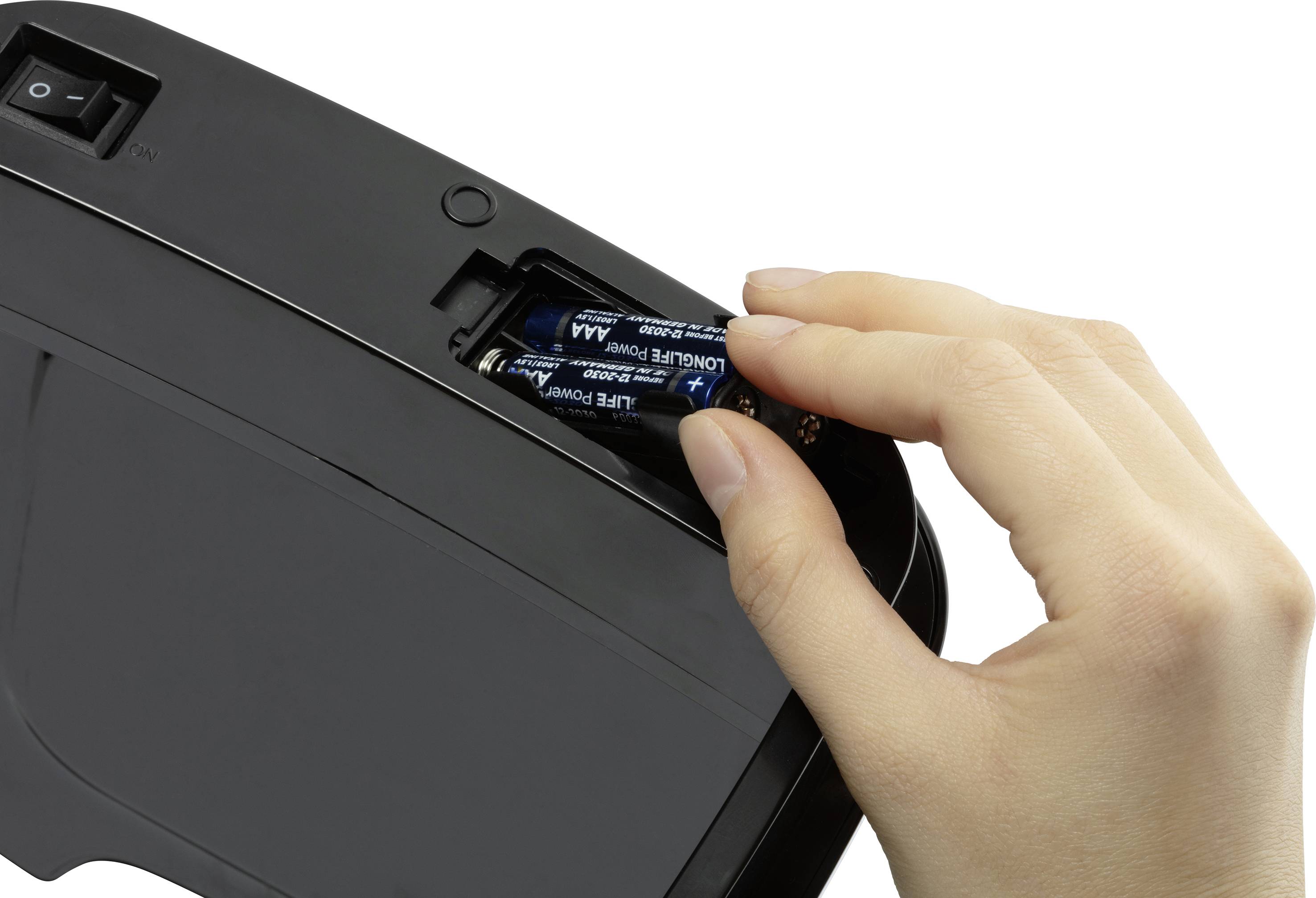 Eine Hand legt zwei AA-Batterien in ein elektronisches Gerät ein.
