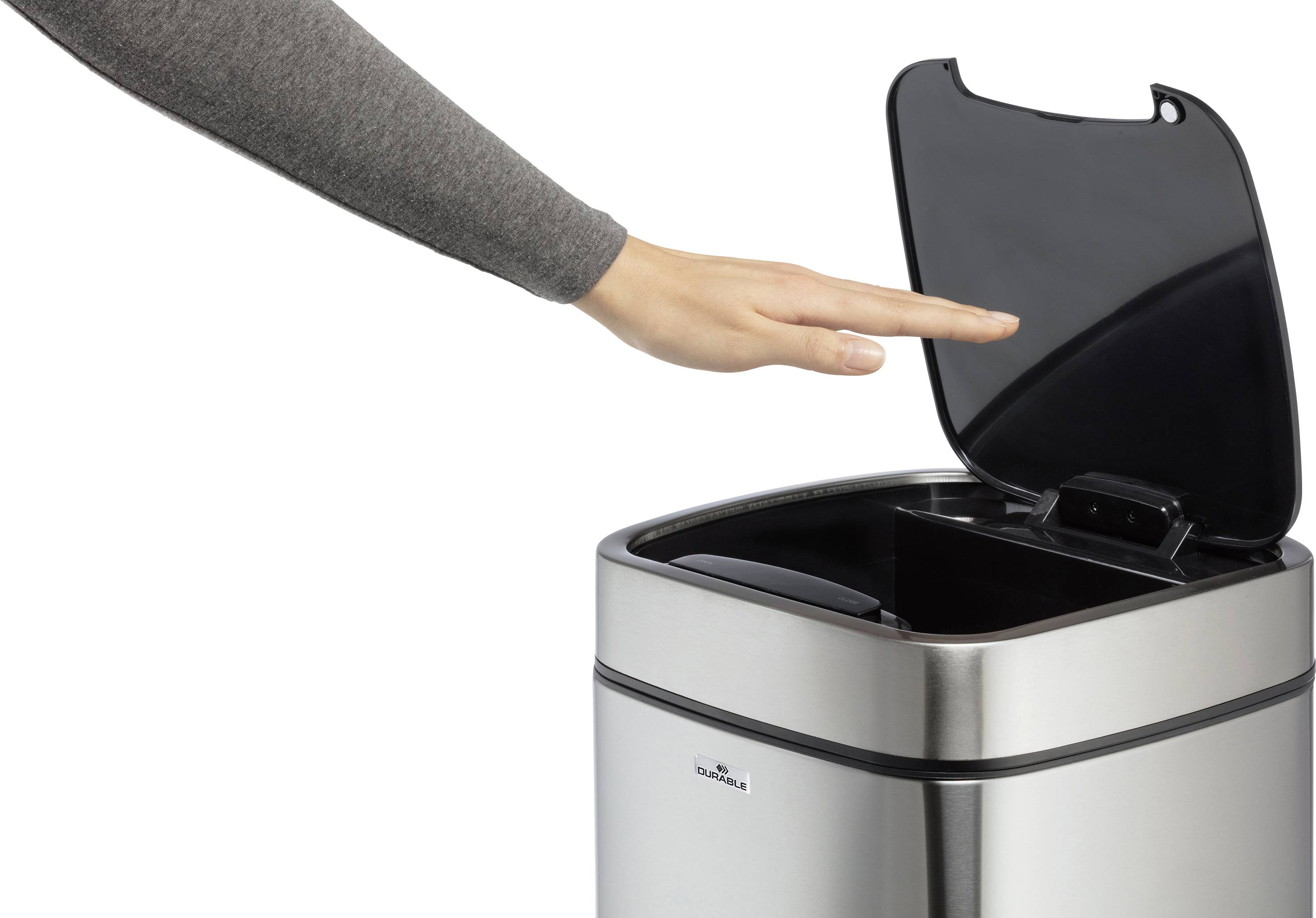 Eine Hand öffnet den Deckel eines silbernen Mülleimers berührungslos durch eine Bewegungserkennung.