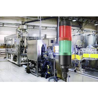 Automatisierte Produktionsanlage mit einem dreifarbigen Signalleuchten-Turm im Vordergrund, der Statussignale anzeigt.