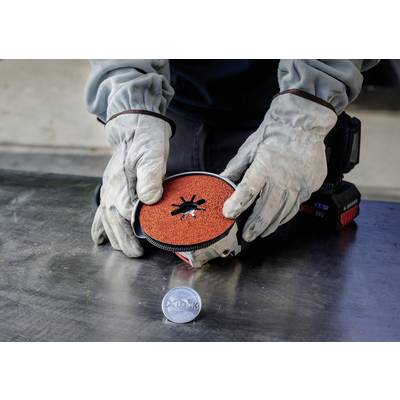 Person mit Schutzhandschuhen wechselt eine Schleifscheibe an einem Elektrowerkzeug auf einer Metallwerkbank.