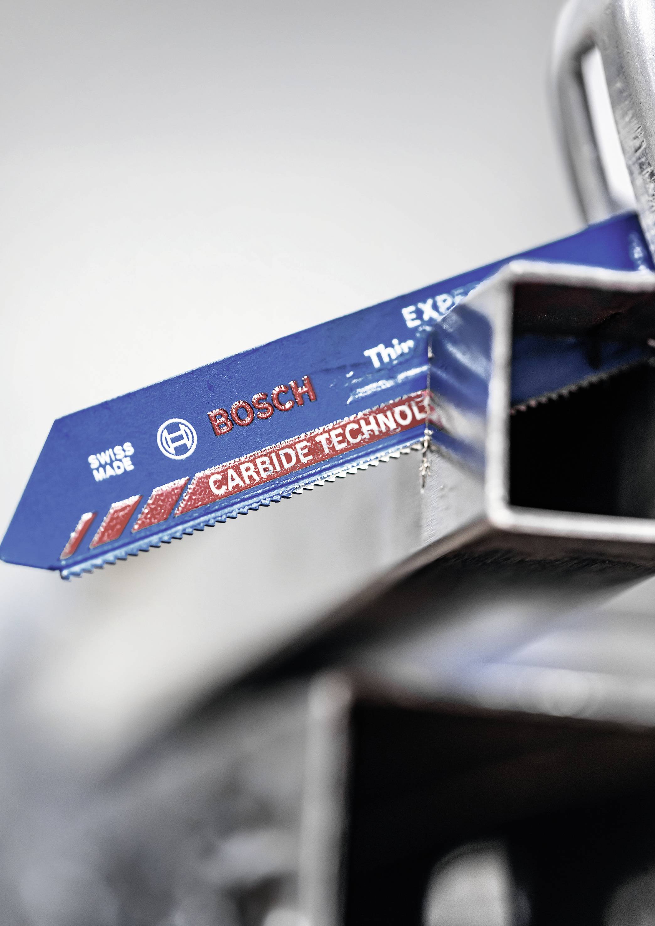 Nahaufnahme eines blauen Bosch-Sägeblatts mit der Aufschrift 'Carbide Technology' und 'Swiss Made', montiert an einem Metallrahmen.