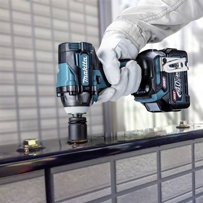 Eine Person arbeitet mit einem akkugetriebenen Schraubenschlüssel von Makita an einem Metallobjekt. Im Hintergrund sind unscharfe Details.