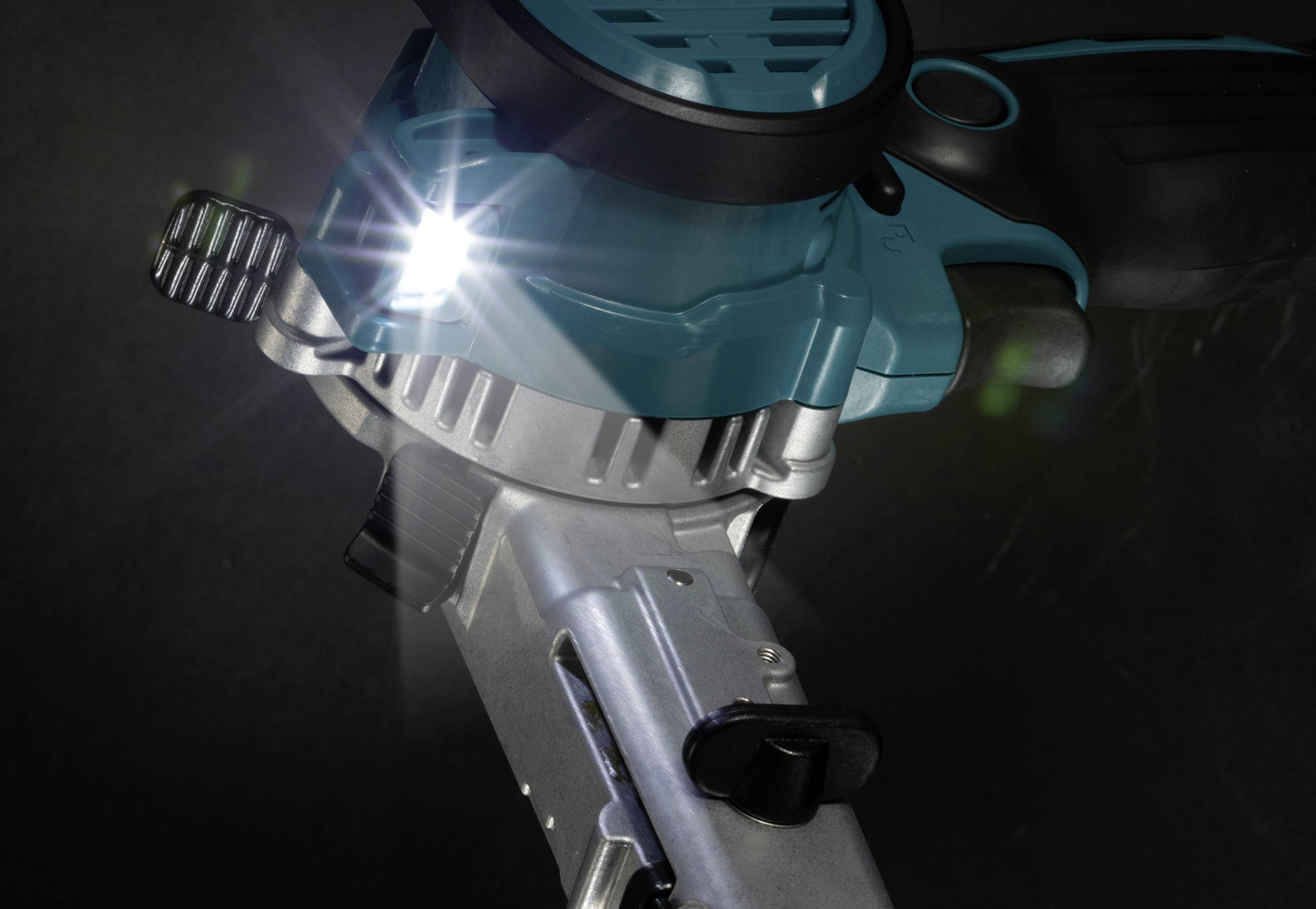 Ein Winkelschleifer in türkisblauem Gehäuse mit funkelndem Lichtpunkt auf der Metalloberfläche.