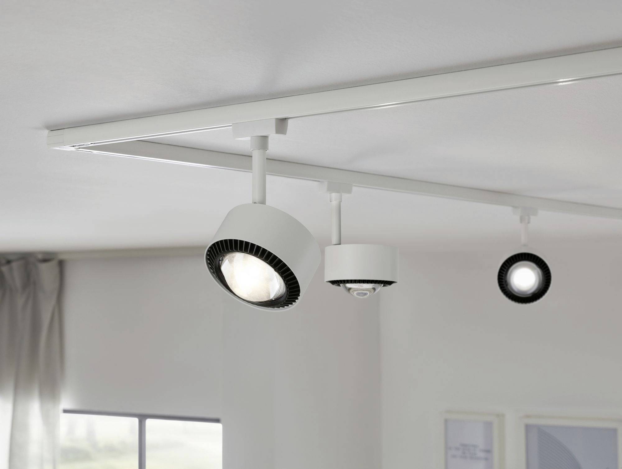 Zwei Deckenstrahler in modernem Design sind an einer Metallschiene montiert, die an einer hellen Zimmerdecke befestigt ist.