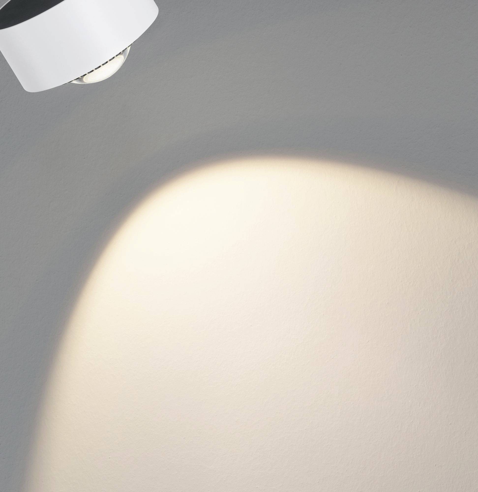 Eine Lampe strahlt Licht auf eine Wand, erzeugt einen hellen Lichtfleck und kontrastiert mit der dunkleren Umgebung im Raum.