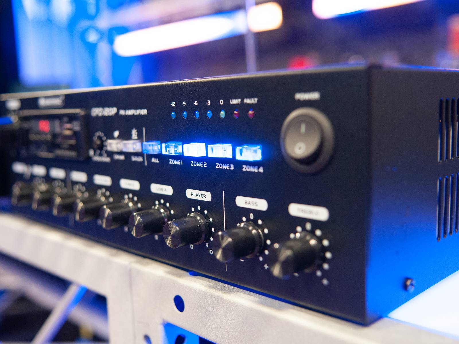 'Nahaufnahme eines Audioverstärkers mit mehreren Drehreglern und digitalen Anzeigen für Zonen. Schalter auf der rechten Seite.'