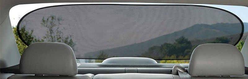 Hintere Autositze mit Blick durch das abgedunkelte Heckfenster. Draußen sind unscharf Bäume und Hügel erkennbar.