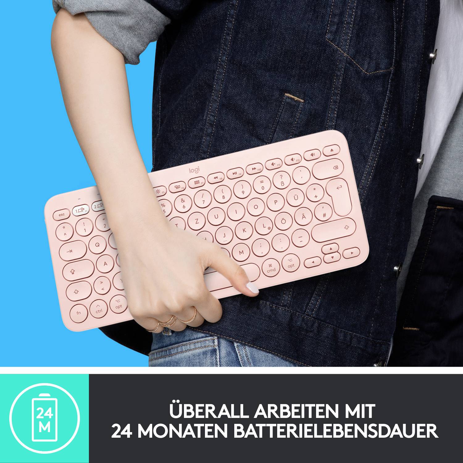 Eine Person hält eine kabellose Tastatur über dem Arm. Text auf der Tastatur: 'ÜBERALL ARBEITEN MIT 24 MONATEN BATTERIELEBENSDAUER'.