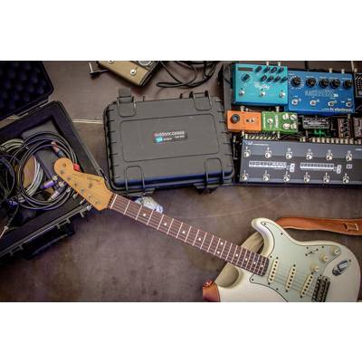 Eine E-Gitarre liegt neben mehreren benutzten Effektpedalen und Kabeln auf dem Boden, die für eine musikalische Performance bereitstehen.
