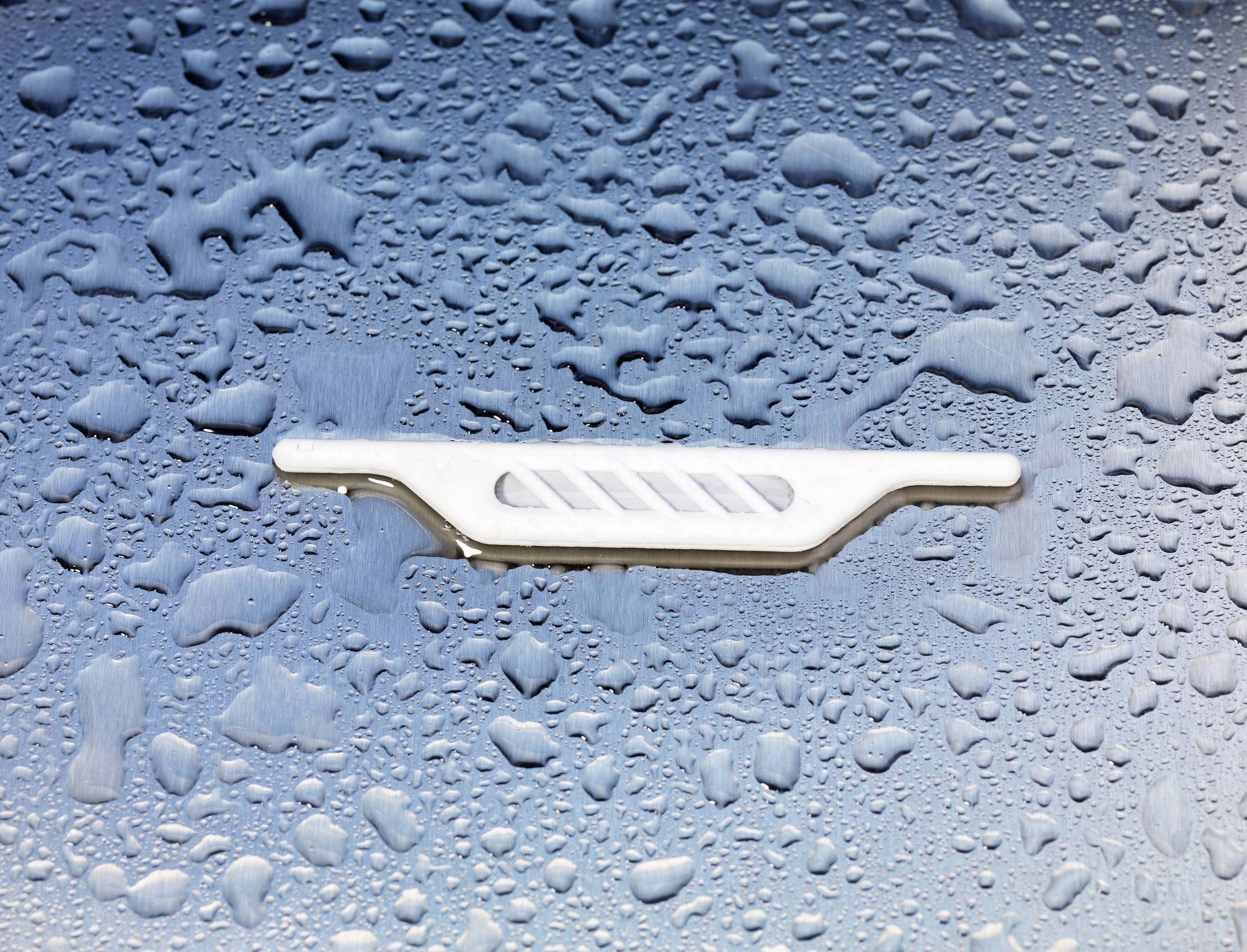 'Nasser Autolack mit Wassertropfen und einer verchromten Verzierung in der Mitte.'