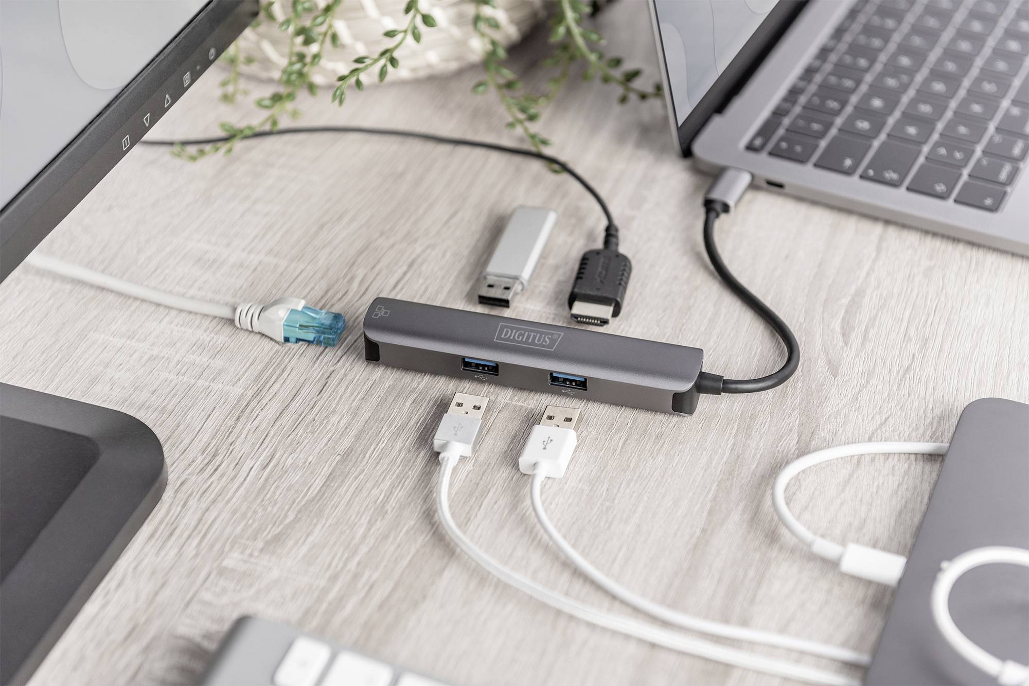 Ein USB-Hub auf einem Tisch verbindet mehrere Geräte, darunter Laptops und USB-Sticks, über verschiedene Kabel und Anschlüsse.