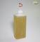 Plastikflasche mit rotem Ausguss und gelblich-brauner Flüssigkeit, stehend vor grauem Hintergrund.