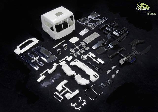 Ein Modellbausatz mit zahlreichen weißen und schwarzen Plastikteilen, die eine Lkw-Kabine und Zubehör darstellen.