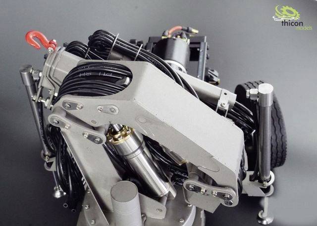 Ein mechanisches Modellbaugerät mit mehreren Armen und Kabeln, das auf einer grauen Oberfläche steht. Oben rechts das Logo 'Thicon Models'.