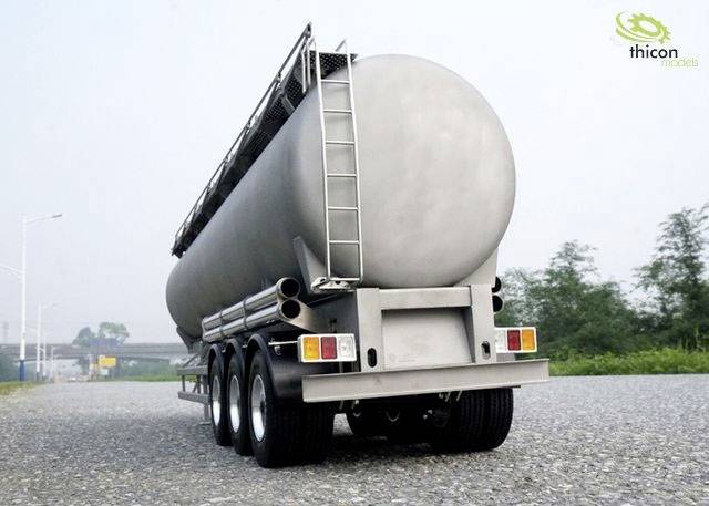 Ein silberner Tanklastwagen auf einem Kiesweg. Im Hintergrund sind Bäume und ein bewölkter Himmel zu sehen.