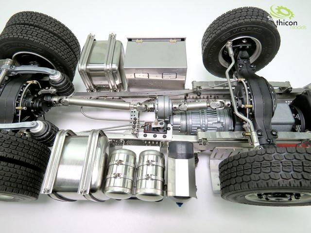 Miniaturmodell eines LKW-Chassis mit Achsen, Federn und Tanks. Detaillierte Ansicht der mechanischen Komponenten auf weißem Hintergrund.