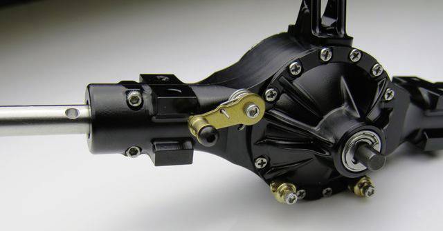 Nahaufnahme eines mechanischen Getriebes mit schwarzen und metallischen Komponenten, montiert auf einer weißen Oberfläche.