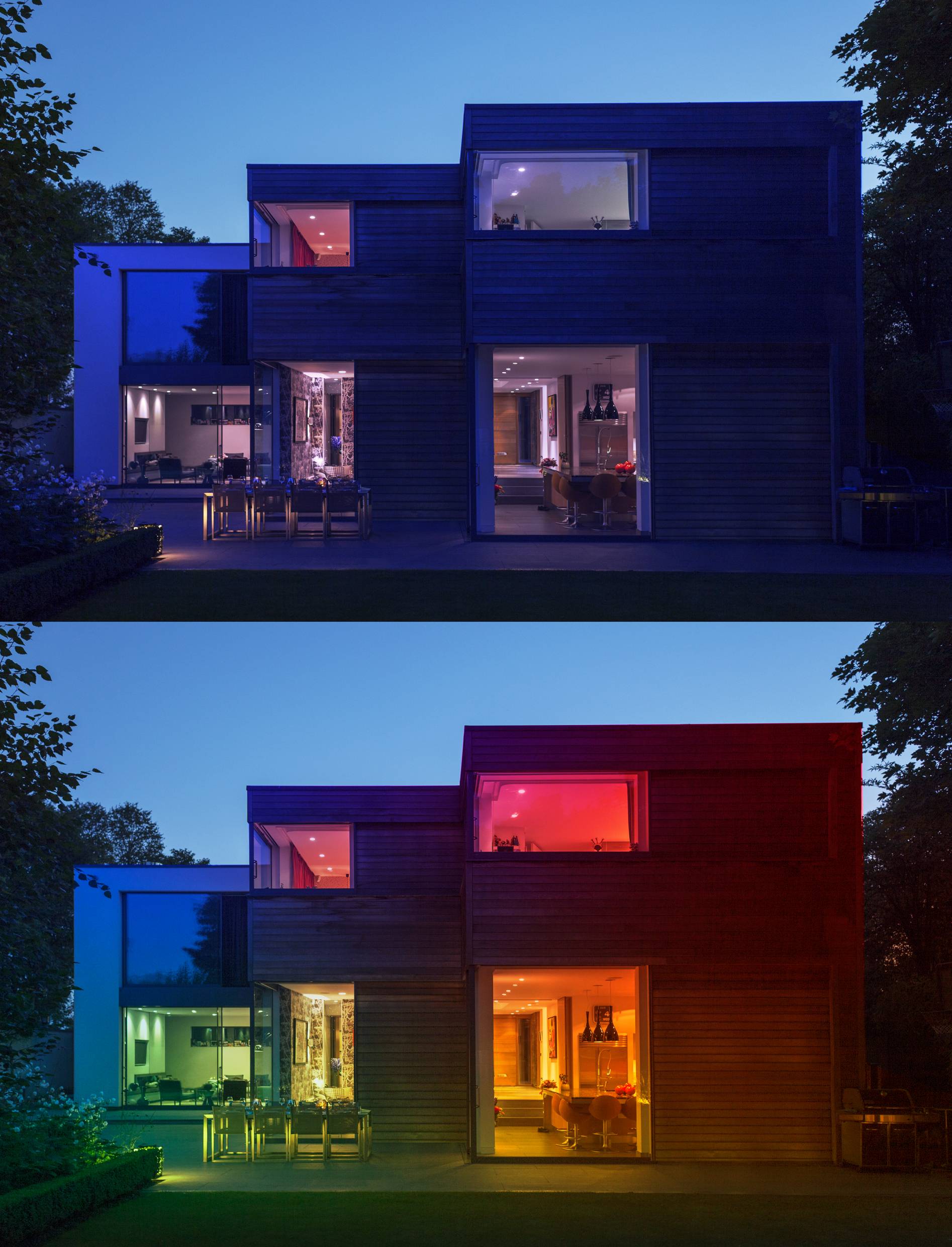 Modernes zweistöckiges Haus bei Dämmerung, oben blau beleuchtet, unten rot beleuchtet, mit großen Fenstern und umgeben von Bäumen.