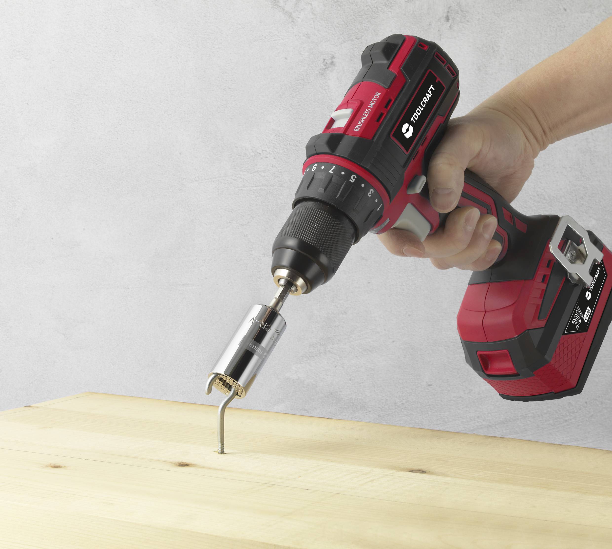 Akkubohrmaschine wird verwendet, um eine Schraube in ein Holzbrett zu drehen. Eine Hand hält die Maschine stabil.