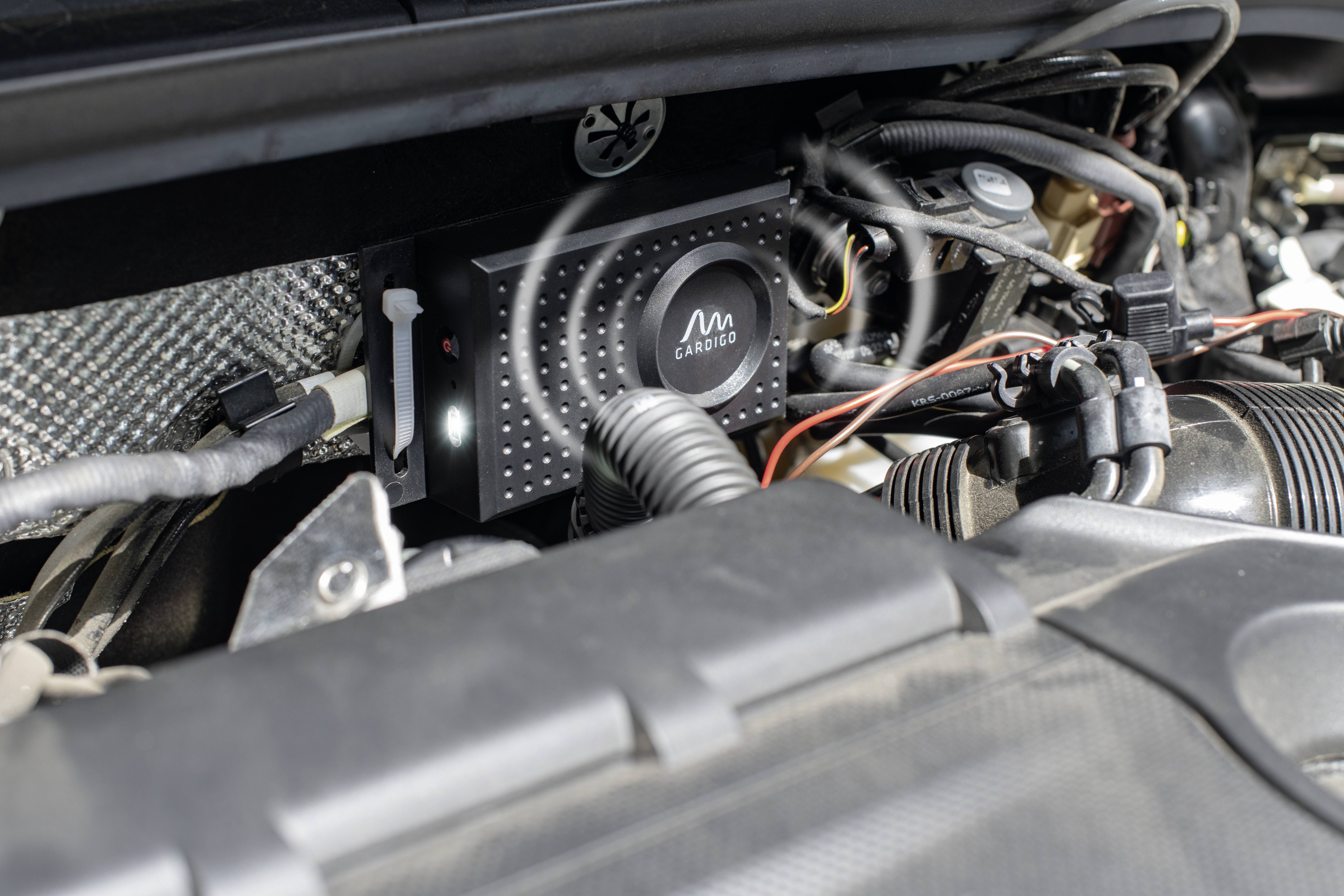 Ein elektronisches Gerät im Motorraum eines Fahrzeugs, mehrere Kabel sind angeschlossen.