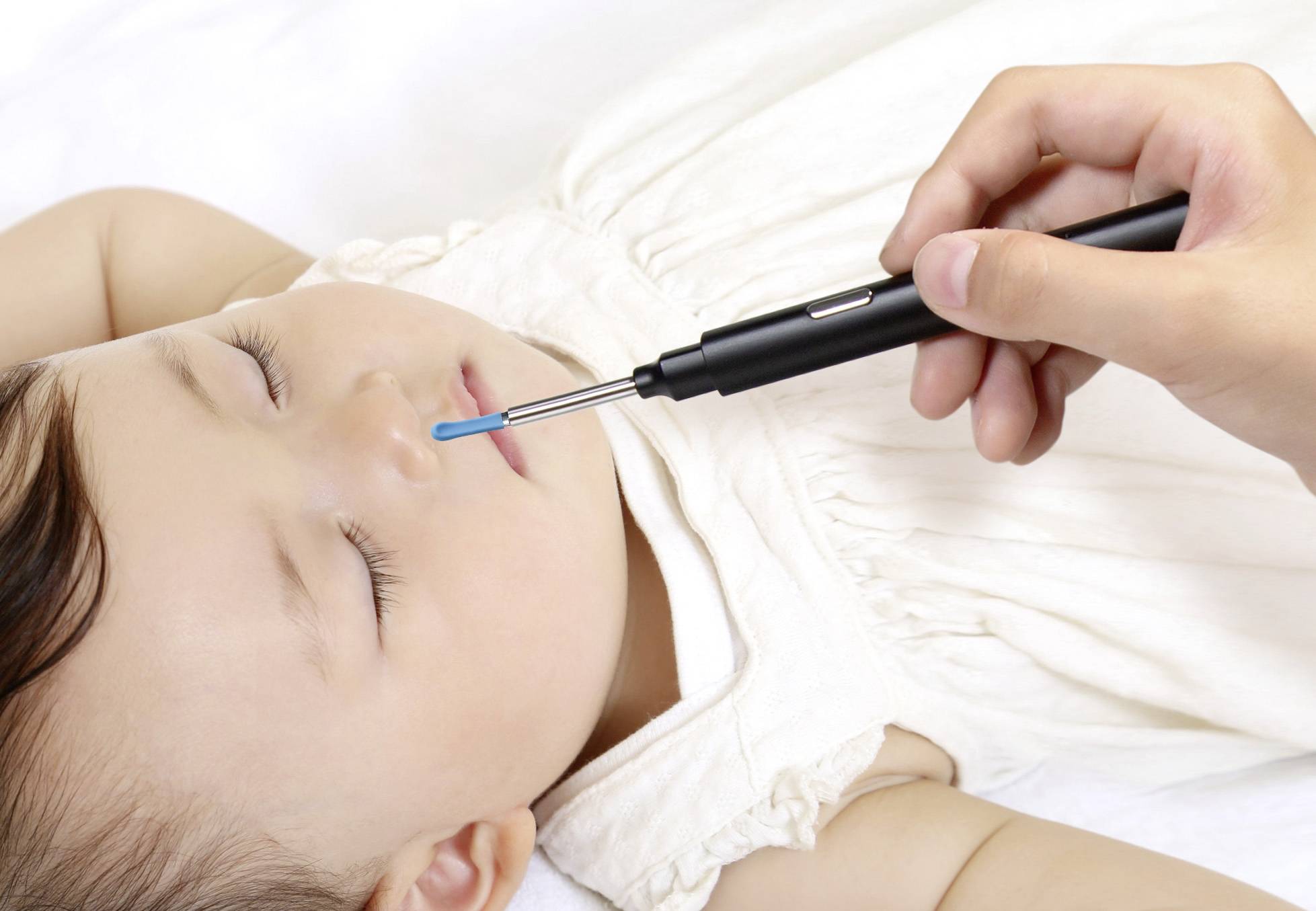 Ein Kleinkind schläft auf dem Rücken, während eine Person mit einem Wattestäbchen ein medizinisches Gerät an der Nase des Kindes verwendet.