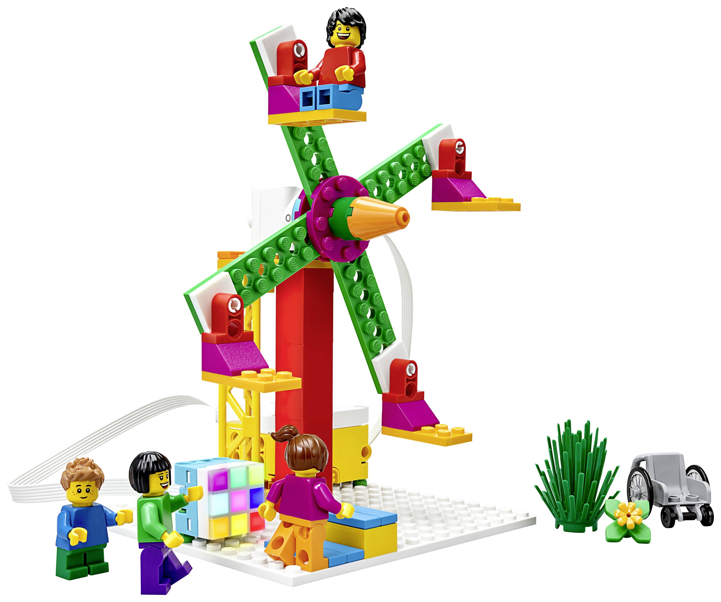 Mehrere Figuren spielen mit einem bunten Lego-Riesenrad-Set. Ein kleiner Spielzeugtraktor und Pflanzen sind ebenfalls zu sehen.