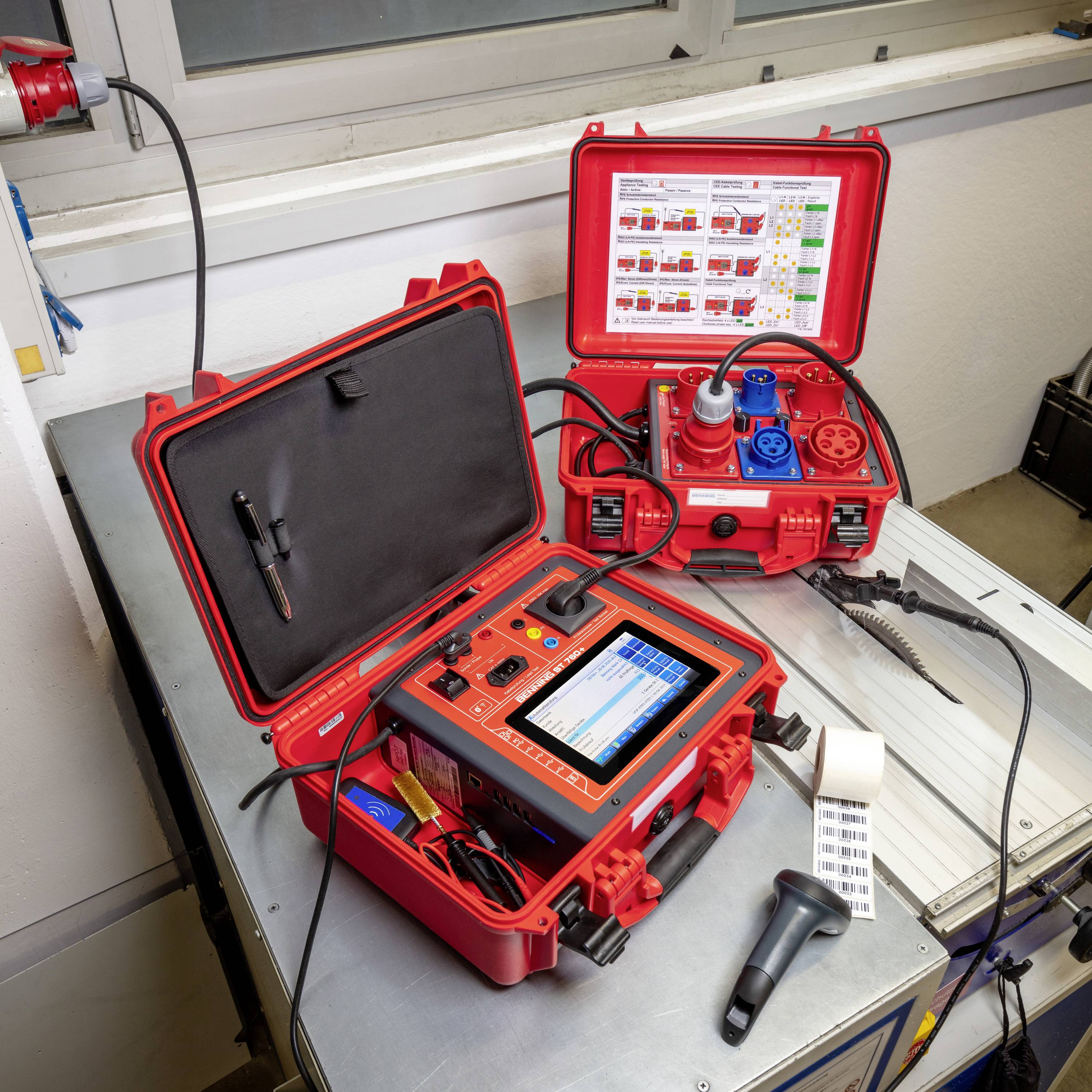 Ein rotes Diagnosegerät mit Display und Kabeln auf einem Tisch in einer Werkstatt, umgeben von Werkstattausrüstung und Kabeln.