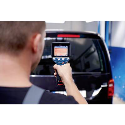 Ein Mann misst mit einem digitalen Gerät die Temperaturen auf einem schwarzen Fahrzeug, möglicherweise zur Überprüfung oder Wartung.