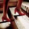 Eine Person geht eine Treppe hinauf, die rote Schuhe trägt. Die Treppe hat eine Marmorstufe.