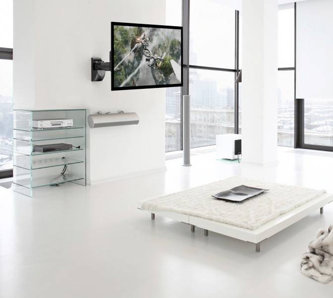 Helles Wohnzimmer mit modernen, minimalistischen Möbeln. An der Wand hängt ein großer Fernseher. Draußen ist eine winterliche Stadtlandschaft sichtbar.