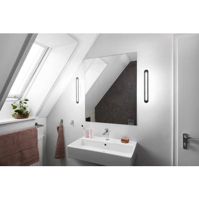 Modernes Badezimmer mit weißem Waschbecken, großem rechteckigem Spiegel und Wandleuchten. Pflanze auf dem Fensterbrett.