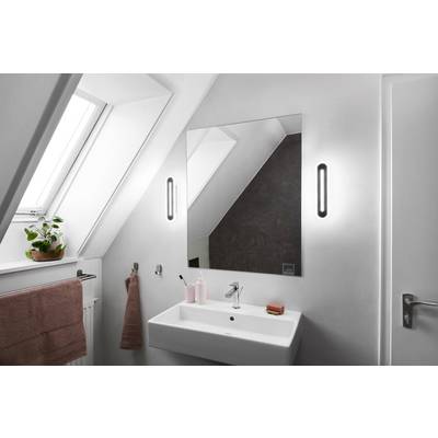 Ein modernes Badezimmer mit schrägem Dachfenster. Großer Spiegel, rechteckiges Waschbecken, und zwei Wandlampen an den Seiten des Spiegels.