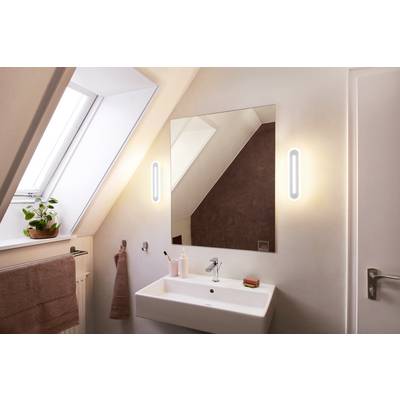 Modernes Badezimmer mit großem Spiegel, Waschbecken und zwei Leuchten an der Wand. Ein Fenster links bringt Tageslicht herein.