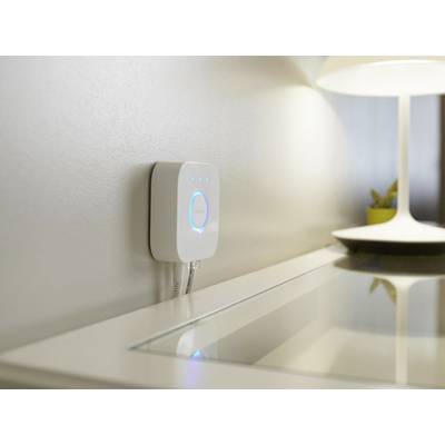 Steuergerät für Smart-Home-Beleuchtung an der Wand, daneben eine eingeschaltete Tischlampe auf einem Schreibtisch.