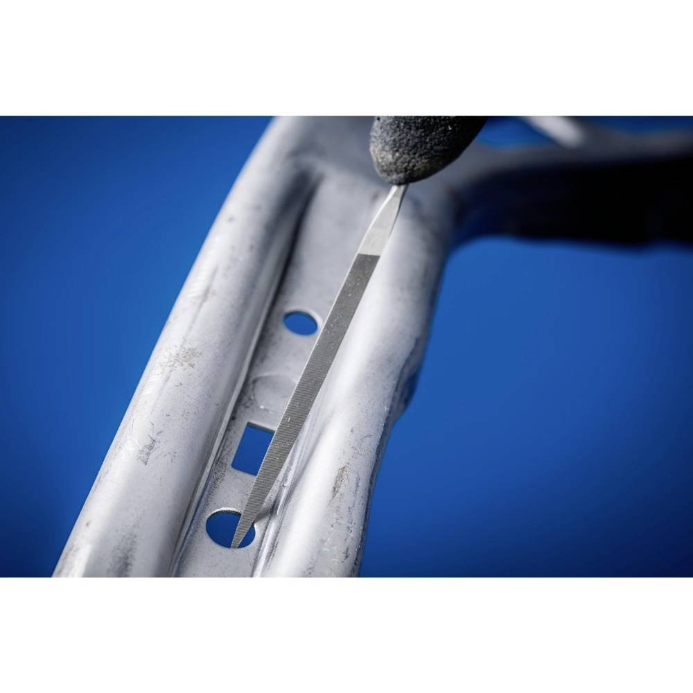 Ein Metallrahmen wird mit einem Werkzeug bearbeitet, um Kerben am Rand zu entfernen. Eine behandschuhte Hand hält das Werkzeug.