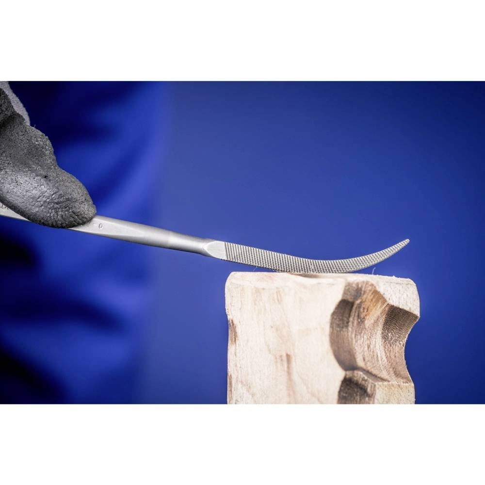 Eine Hand hält eine Feile und bearbeitet ein Holzstück, um Details zu formen. Der Hintergrund ist unscharf und blau.