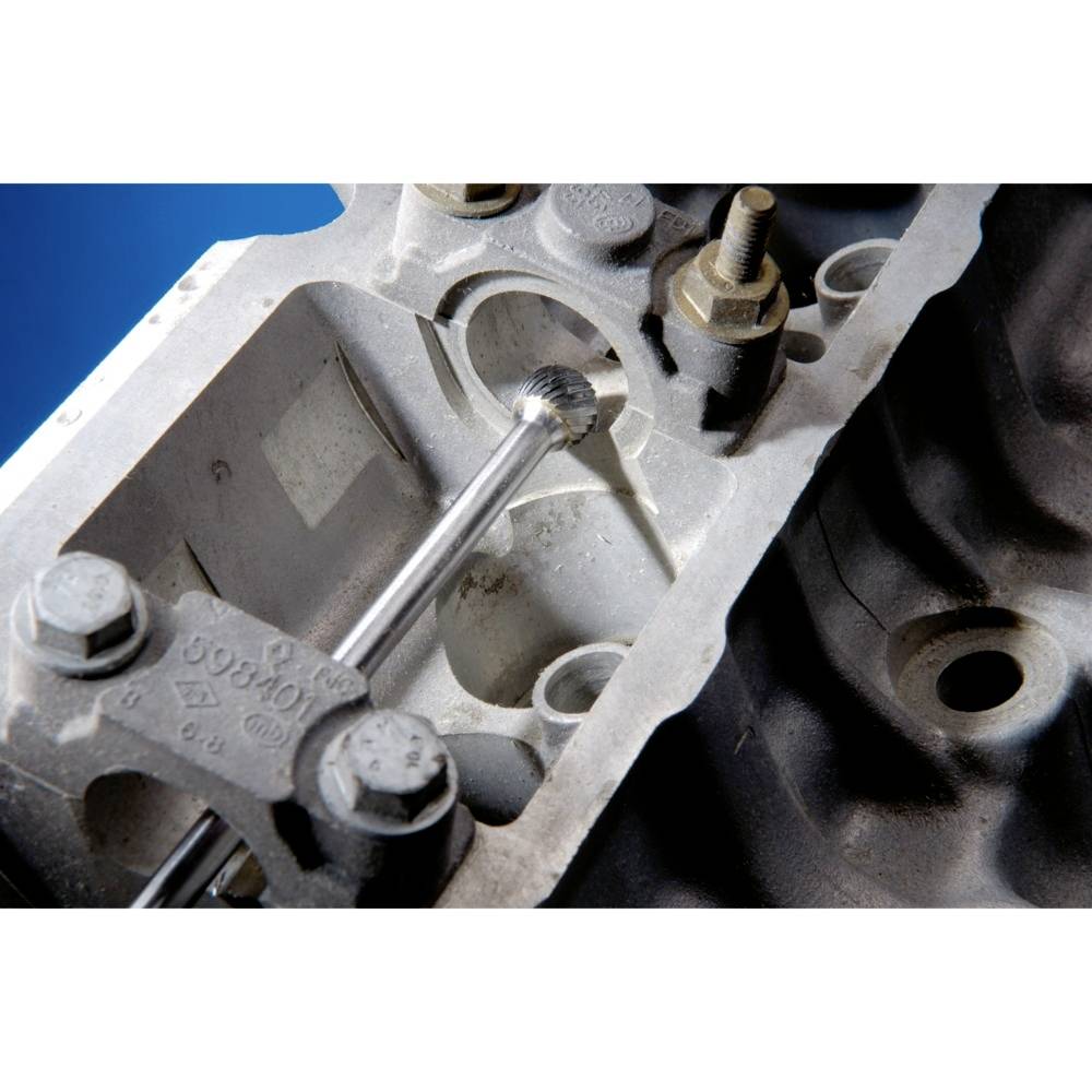 Ein Metallbohrer bearbeitet eine komplexe motorenähnliche Metallstruktur, umgeben von Schrauben und Bolzen.