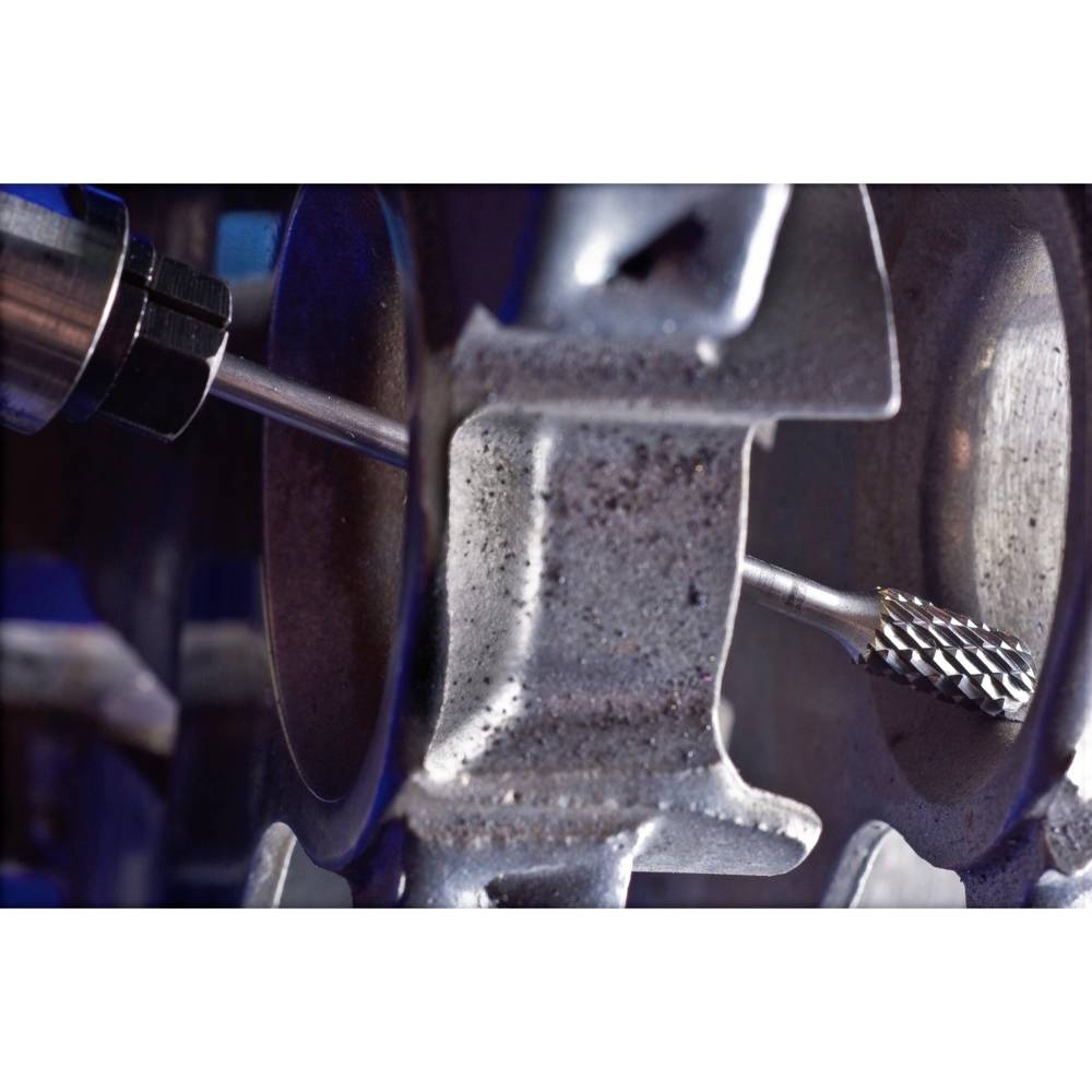 Nahaufnahme eines Werkzeuges beim Fräsen eines Metallteils. Das Werkzeug hat eine rotierende Spitze und bearbeitet die Oberfläche.