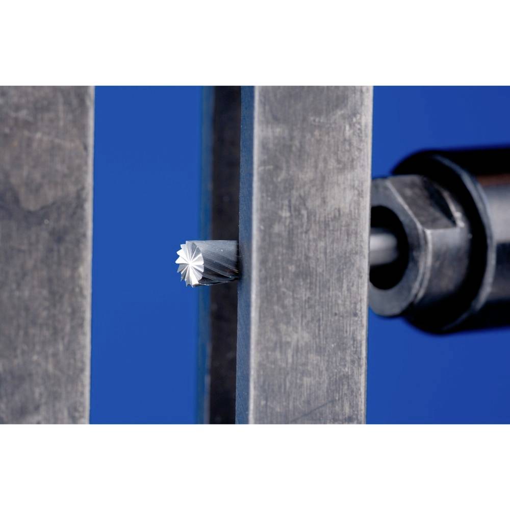 Eine metallische Fräsmaschine schneidet präzise durch ein dünnes Metallstück. Der Hintergrund ist blau.